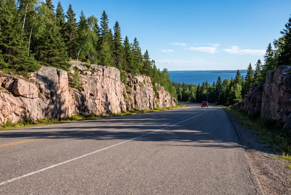 Highway between pink granite rock cuts and spruce
