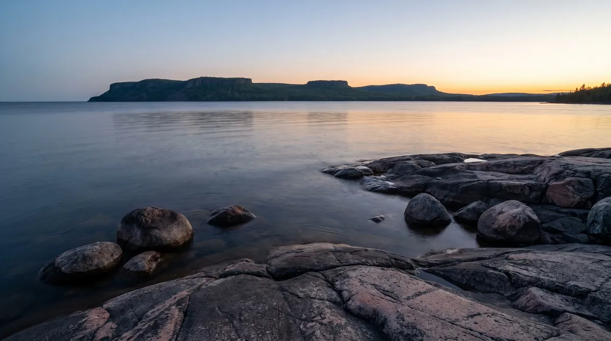 Granite shore at dusk with a flat-topped peninsula