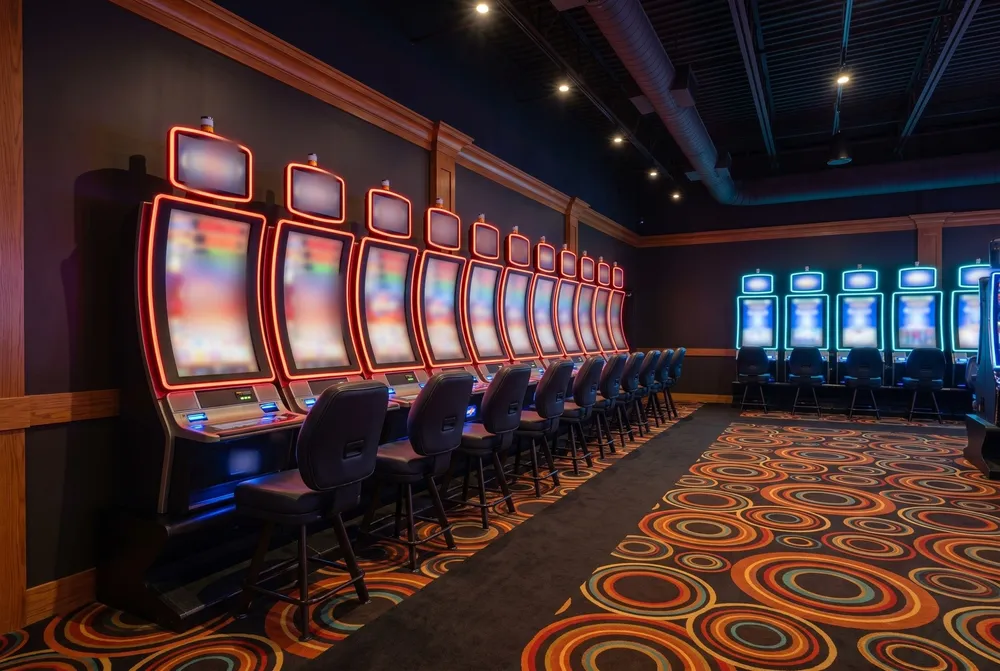 Row of red-lit slot machines with curved screens